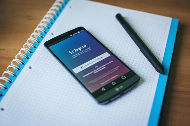 Instagram on a smartphone and a piece of paper with pen